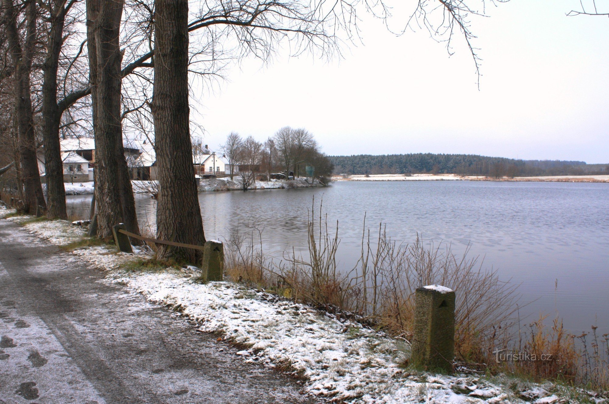 Pohled na rybník z hráze po které vede modře značená turistická cesta