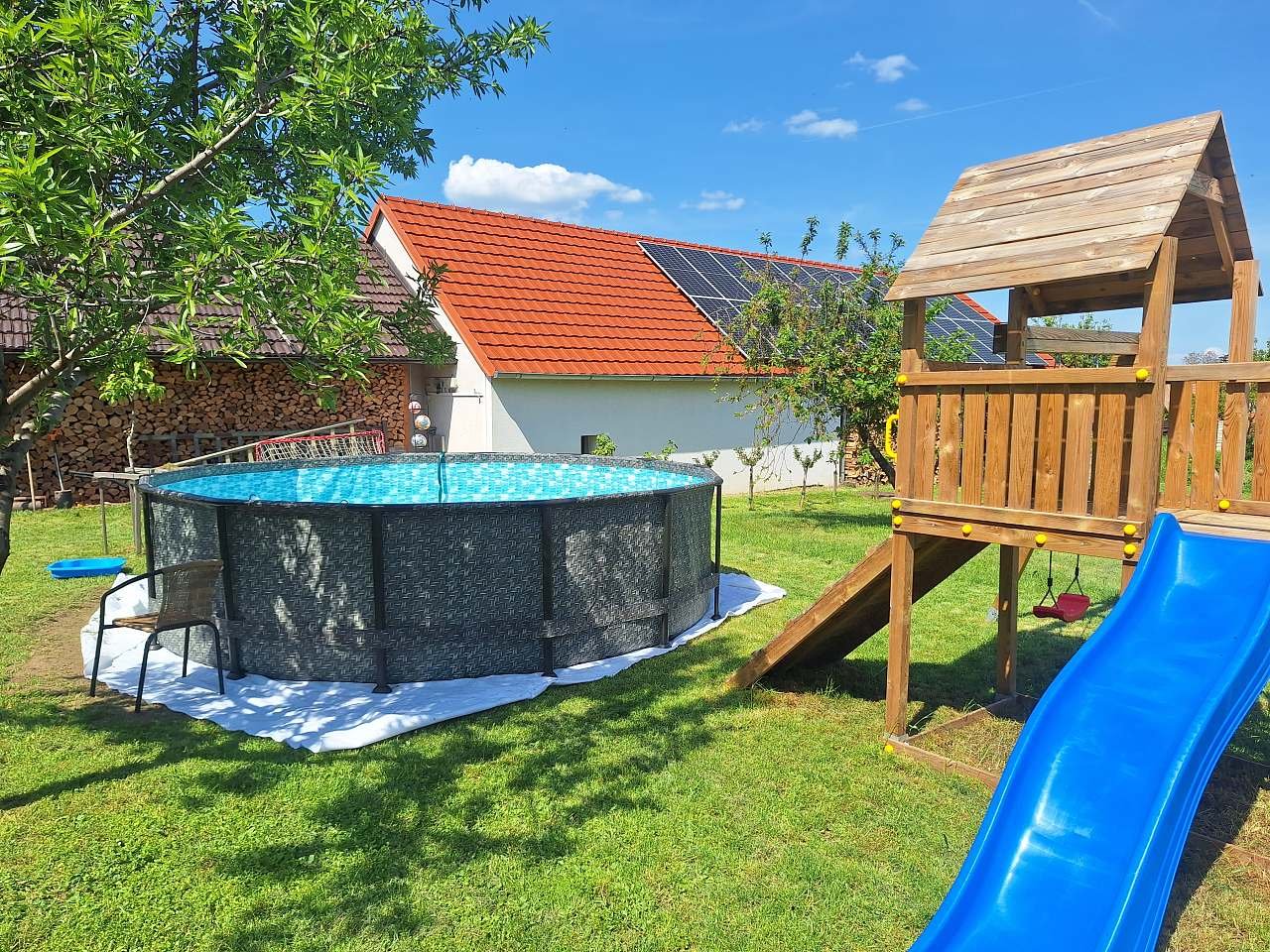 Bazén v zahradě s dětským hřištěm.