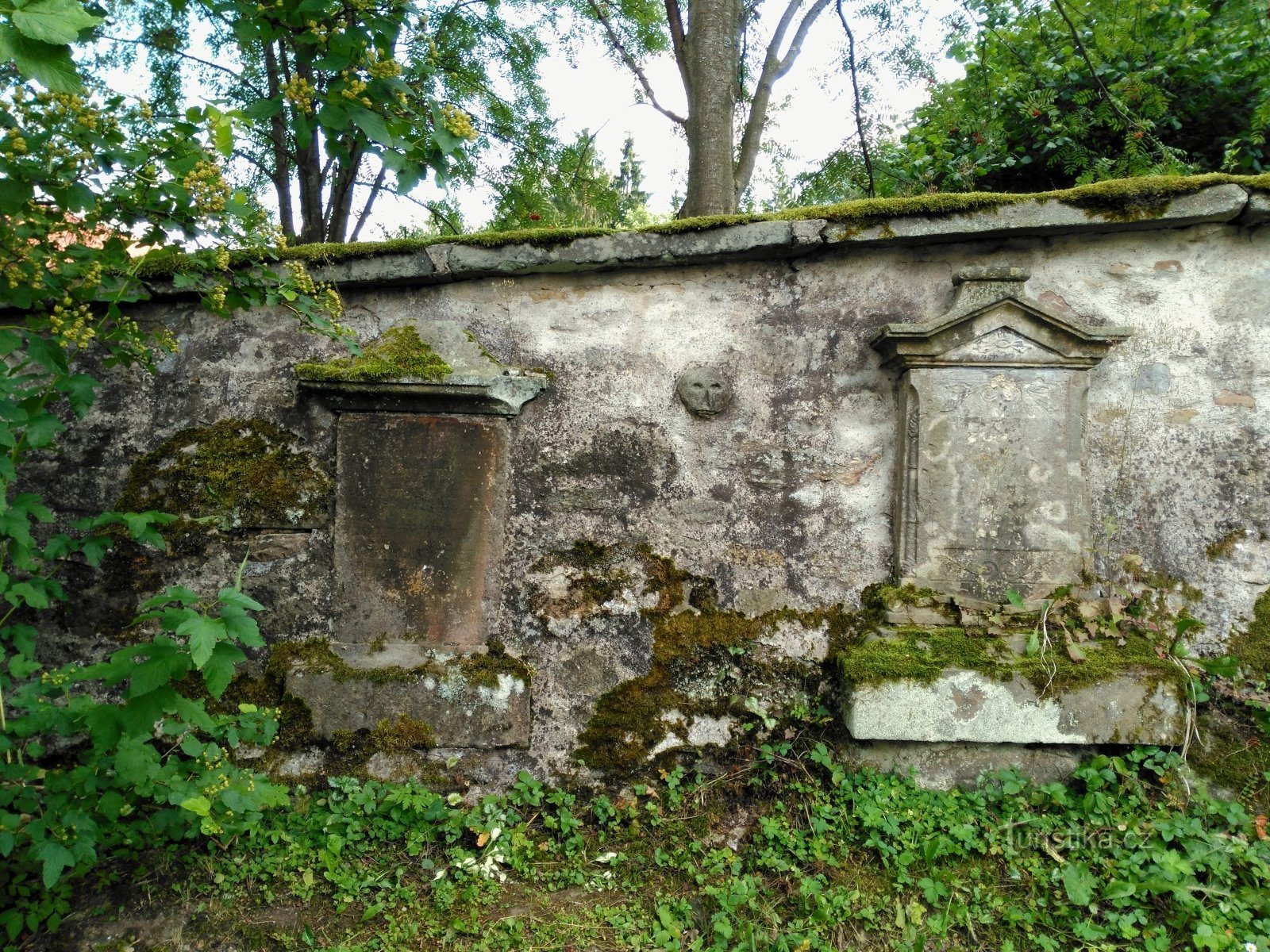 parede do cemitério com cabeça de pedra esculpida.