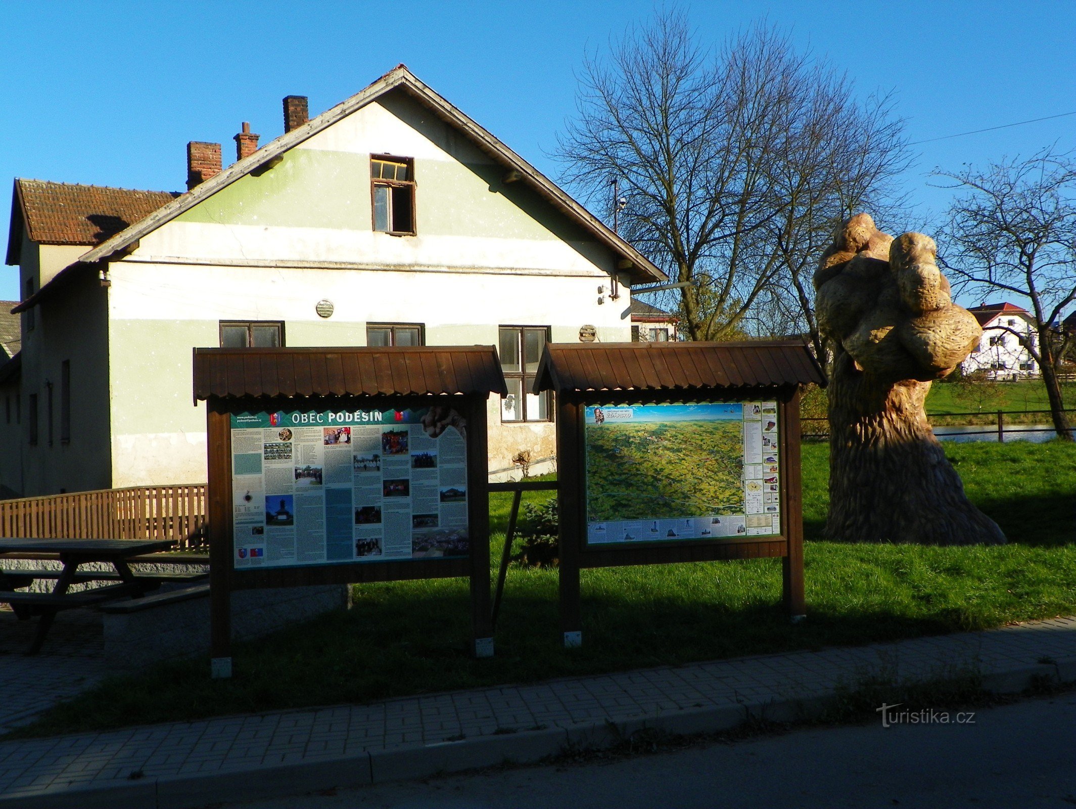 Panou informativ lângă copacul de beton din Poděšín