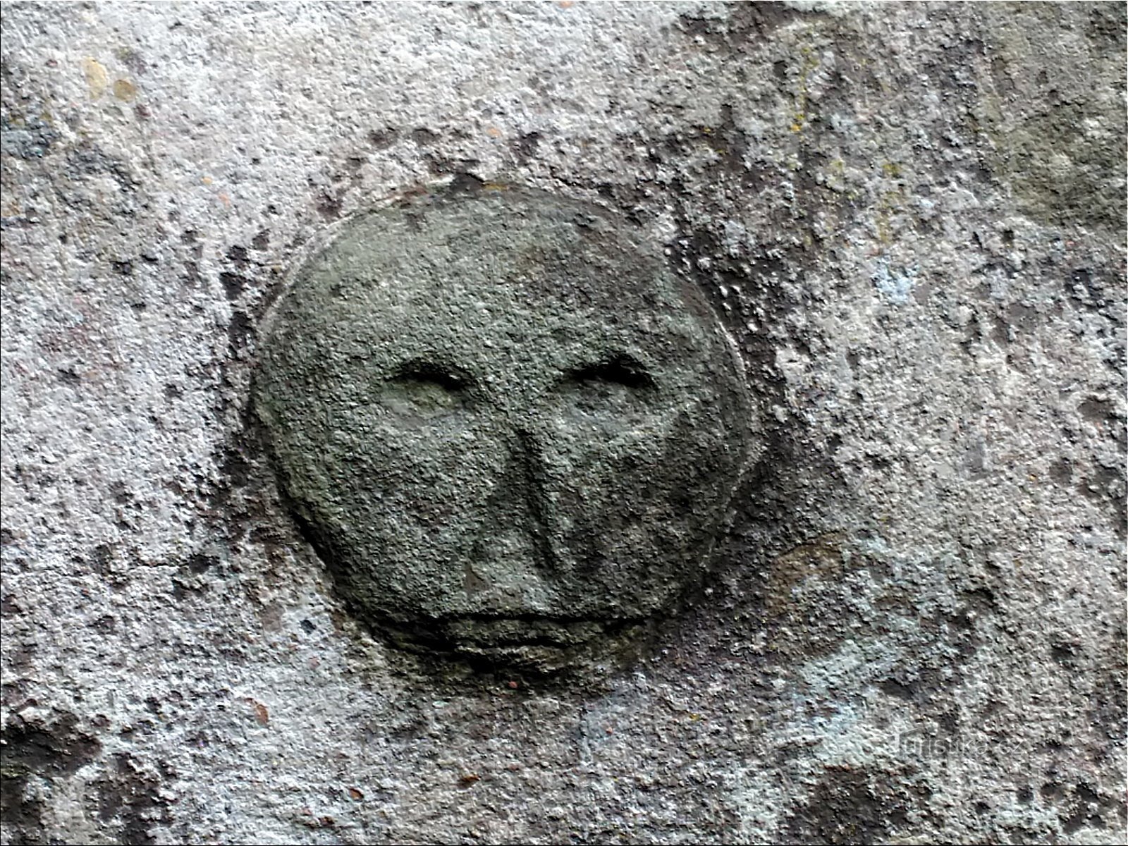 kamenná hlava ve hřbitovní zdi.