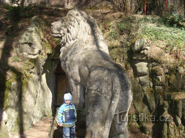 leão de pedra em frente à entrada da caverna