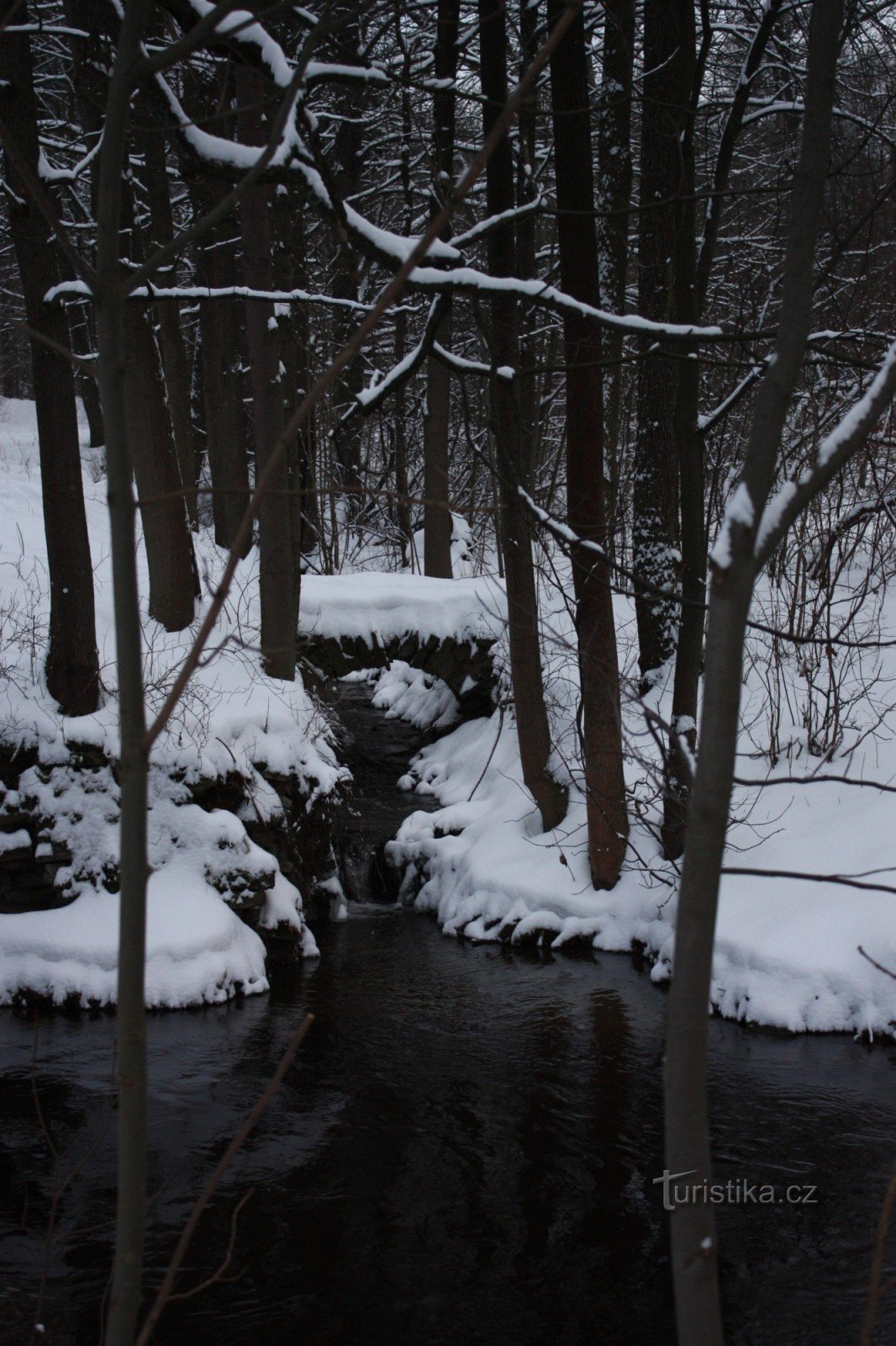 Eine Steinbrücke über einen Bach im Schlosspark