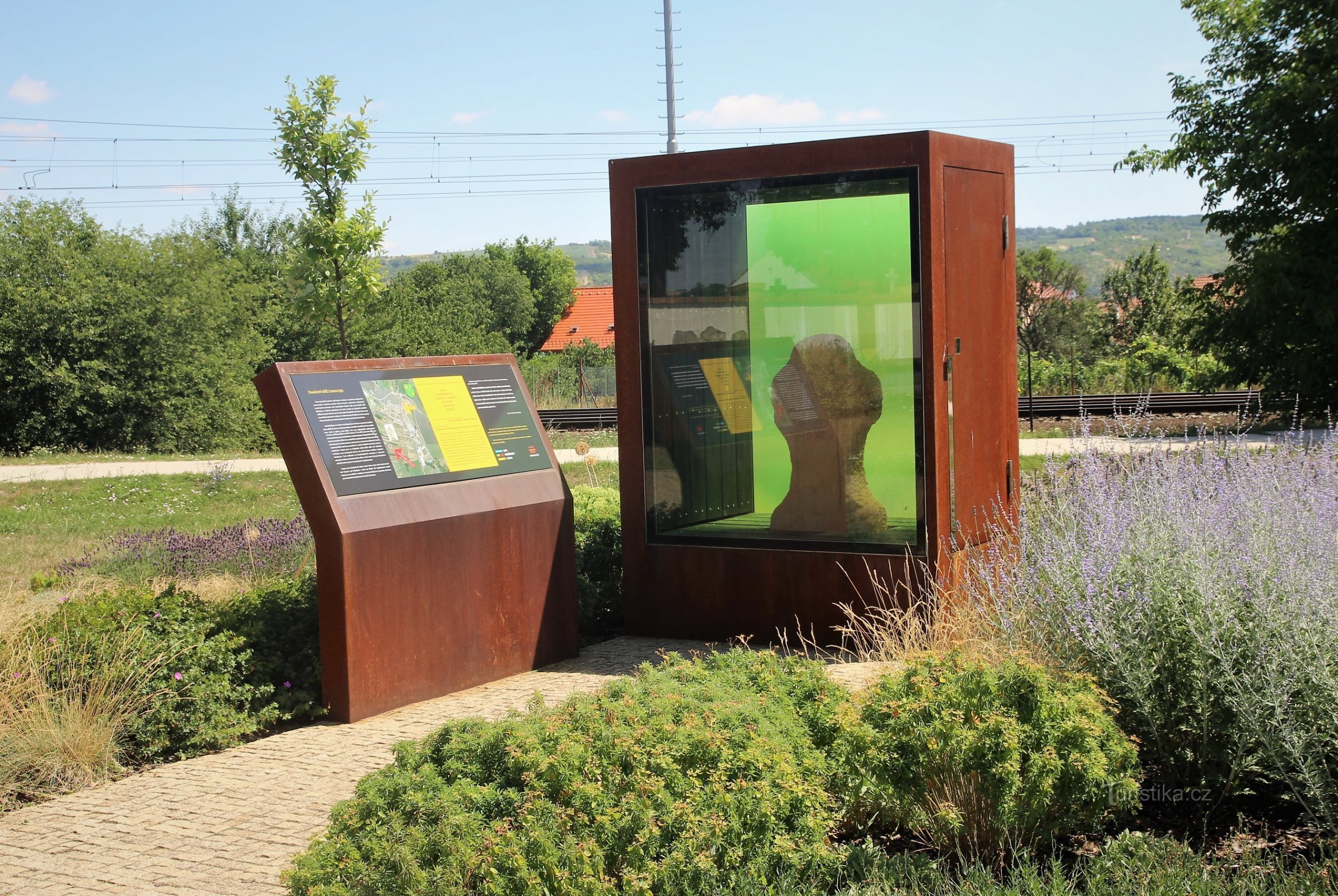 Une copie de la croix de pierre historique dans une vitrine avec un panneau d'information