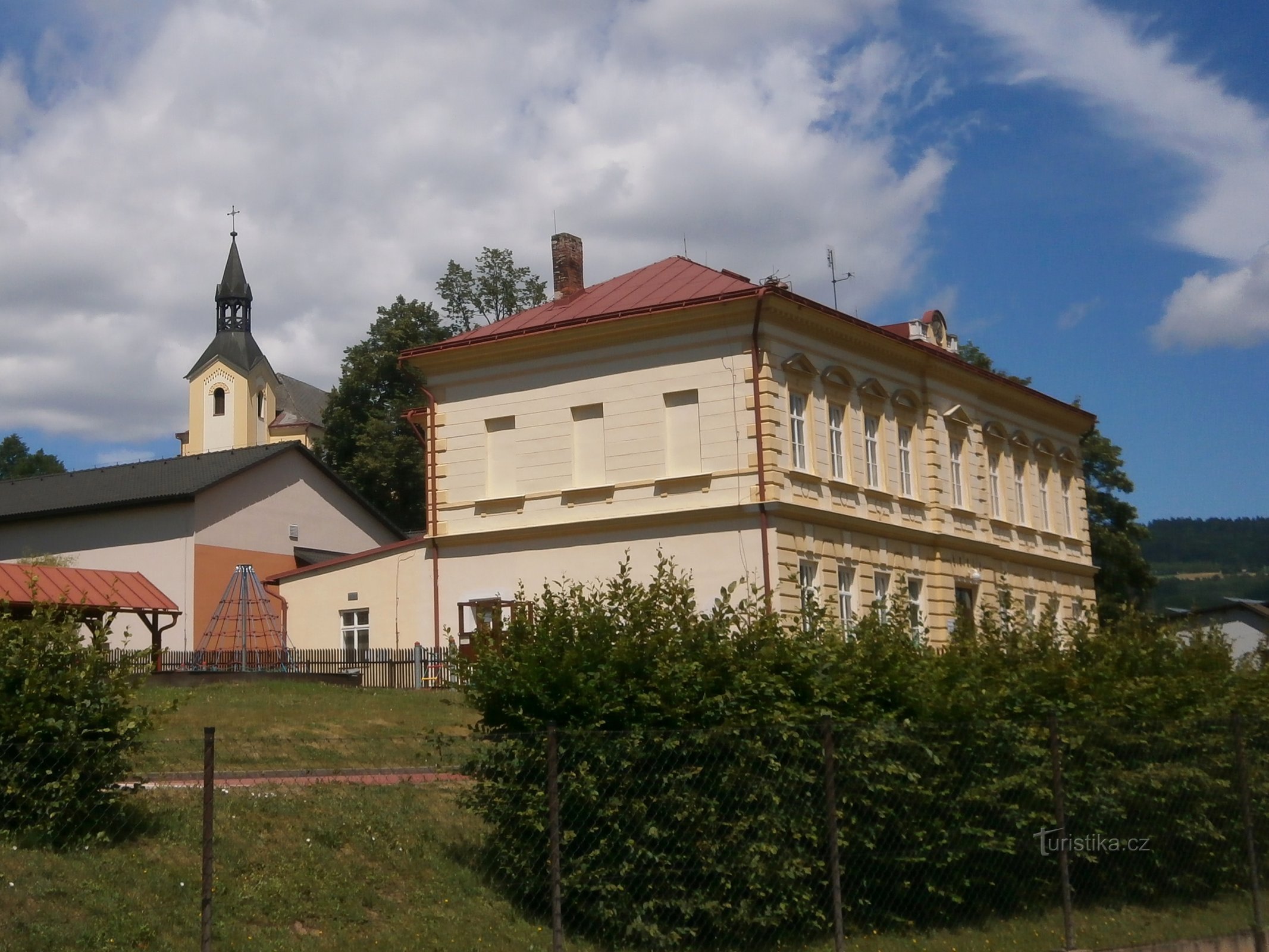 Iglesia de San Bartolomé, el Apóstol con un edificio escolar (Batňovice)