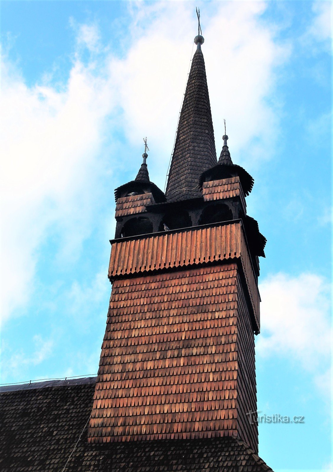 Ein vierseitiger Kirchturm mit einem konischen Dach mit vier Ecktürmchen