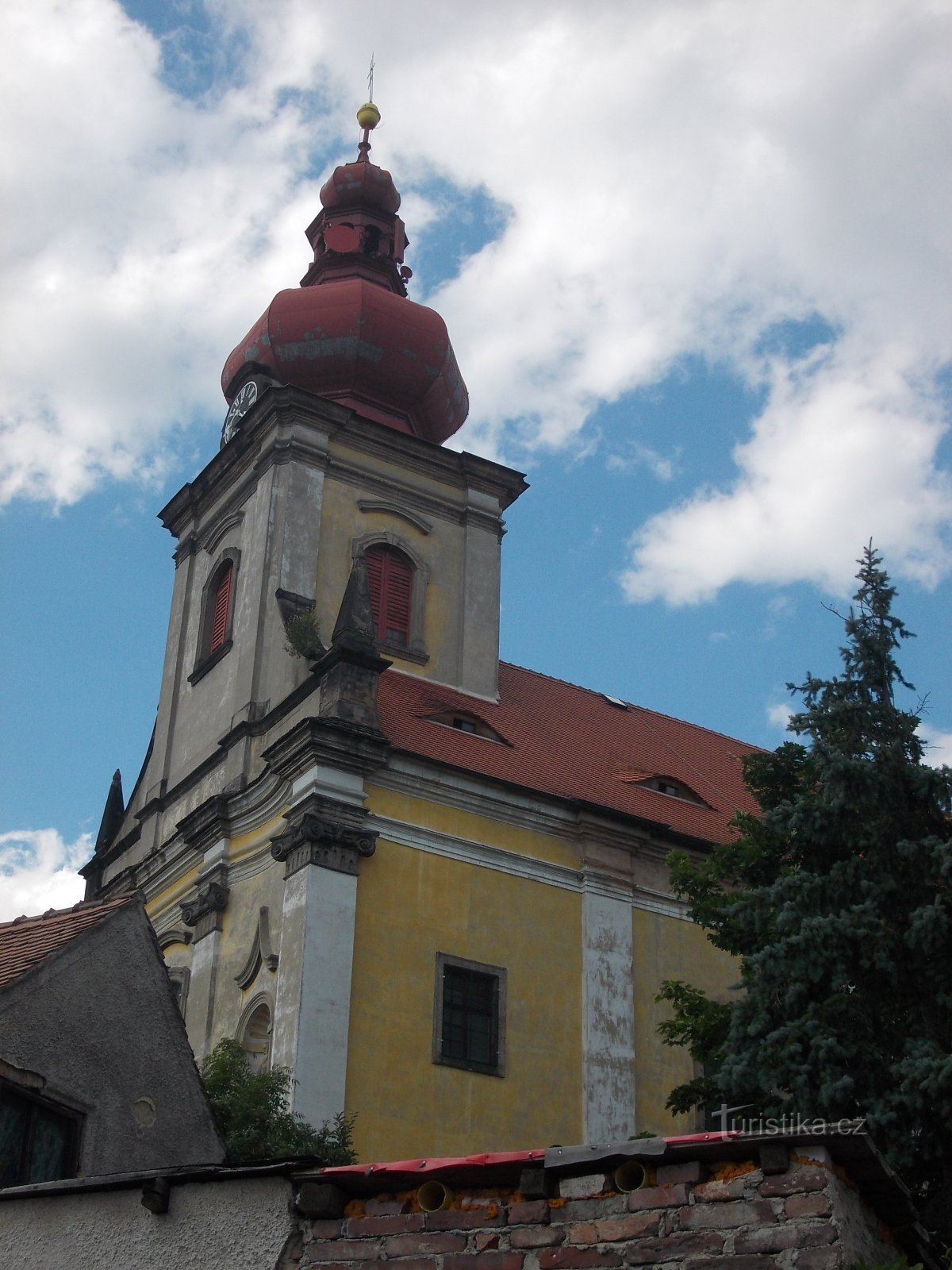 μια εκκλησία με ενσωματωμένο πρισματικό πύργο, στην κορυφή του οποίου ένας πύργος σε σχήμα κρεμμυδιού