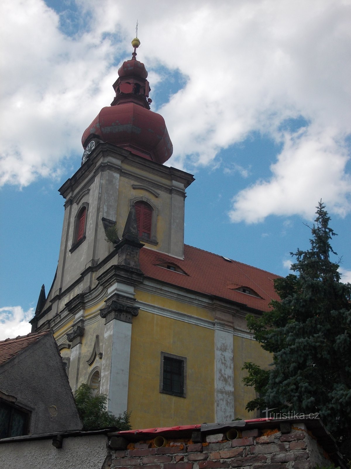 una chiesa con torre prismatica incorporata, sormontata da una torre a cipolla