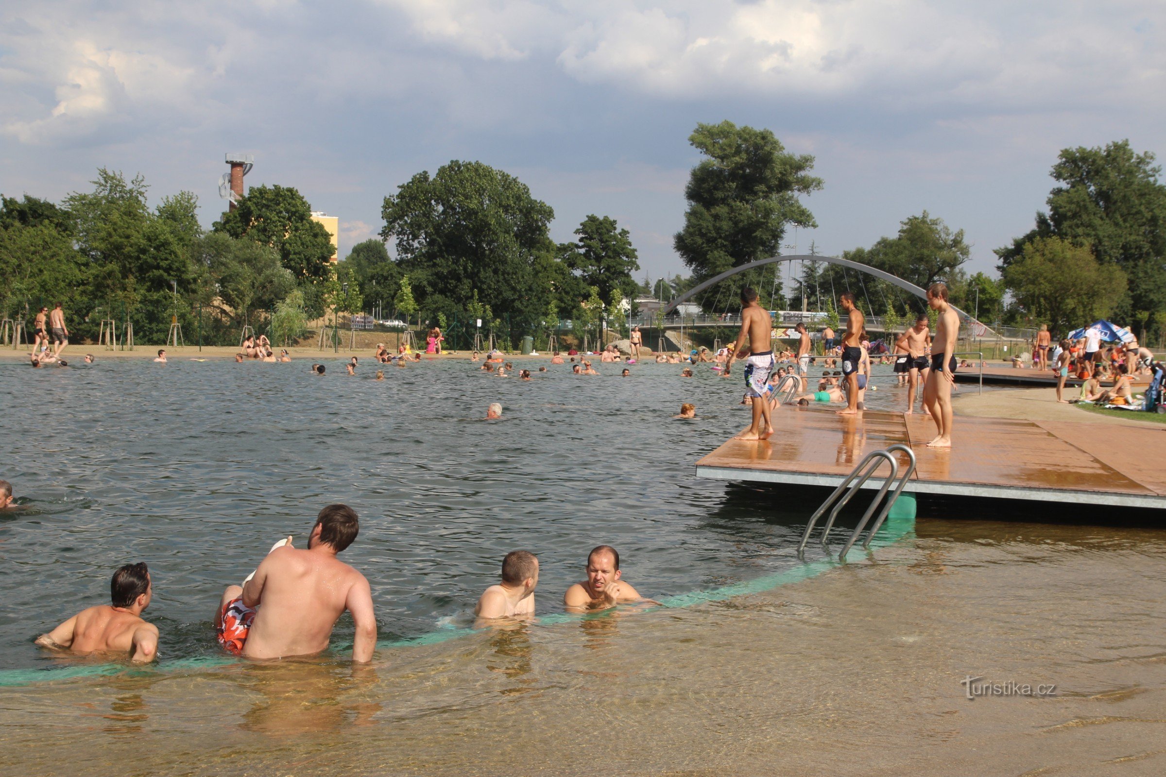 The swimming pool is located near the new cycle bridge over the river Svratka, in the background