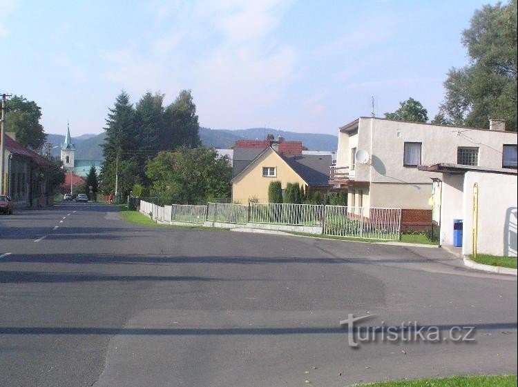 Kozlovice: Näkymä kylän tielle, bussipysäkki oikealla, taustalla paikallinen kirkko