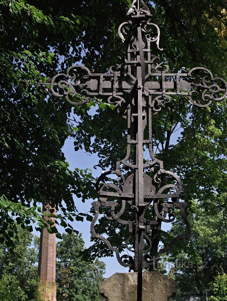 a cross from behind, in the background the chimney of the former Janovice spulkárny