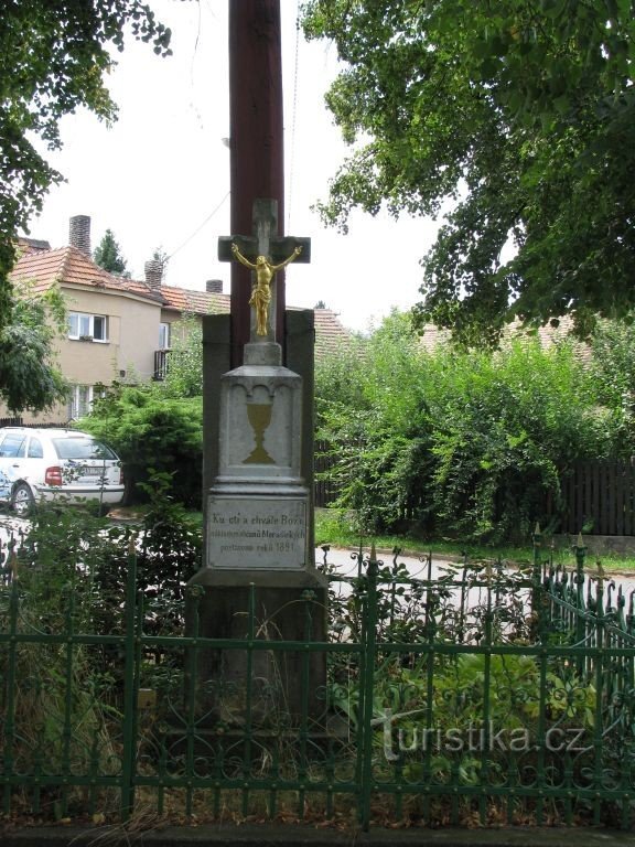 Ein Kreuz und ein Glockenturm im Dorf... Es zeigt sowohl einen gekreuzigten Christus als auch einen Hussitenkelch