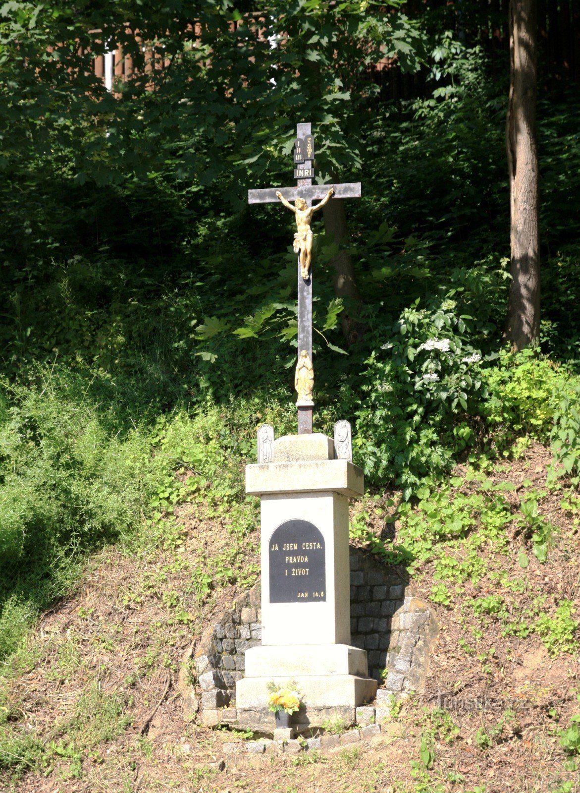 Una croce di ghisa in piedi tra le querce commemorative