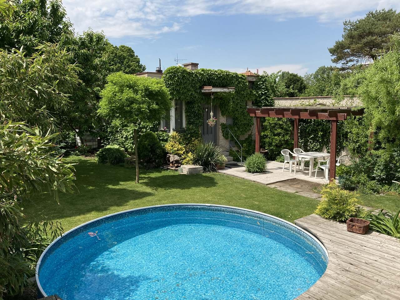 Een klein zwembad in de tuin met een appartement en een open pergola