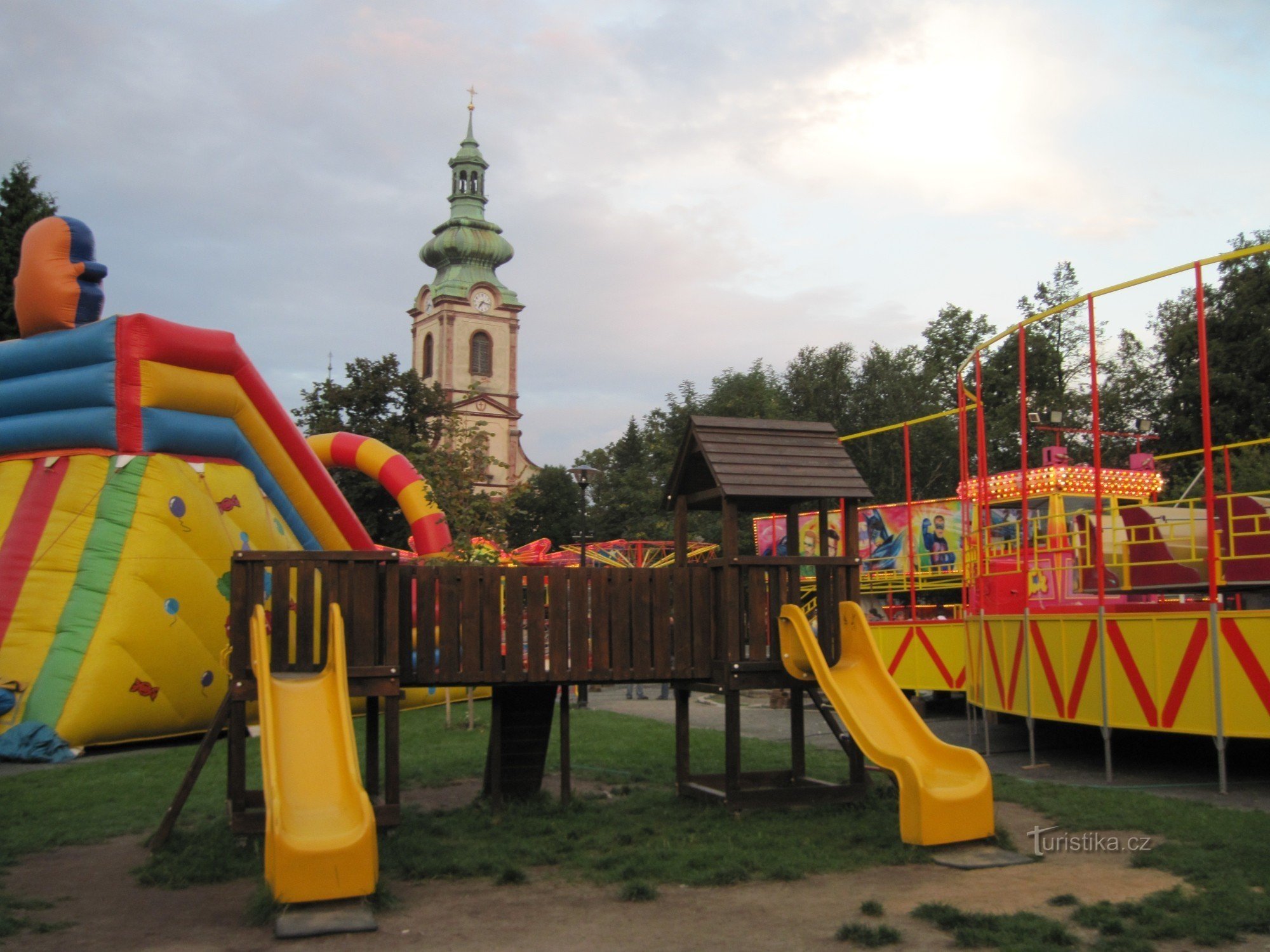 Náměstí Smiřické met kermisattracties, op de achtergrond de kerk van St. Beschermengelen