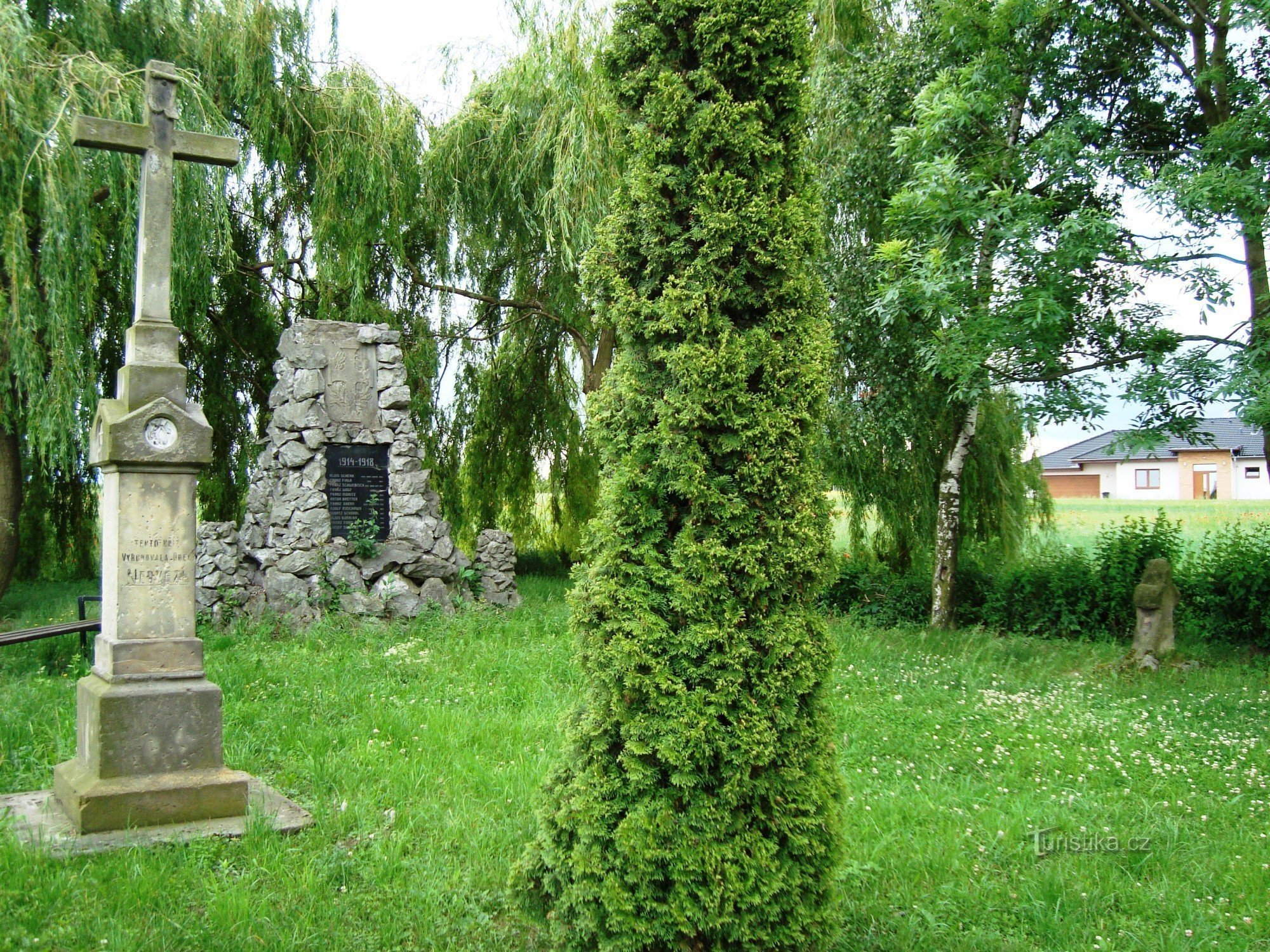 Parque Nedvězí al comienzo del pueblo con una cruz de reconciliación, una cruz de piedra de 1869 y un pom