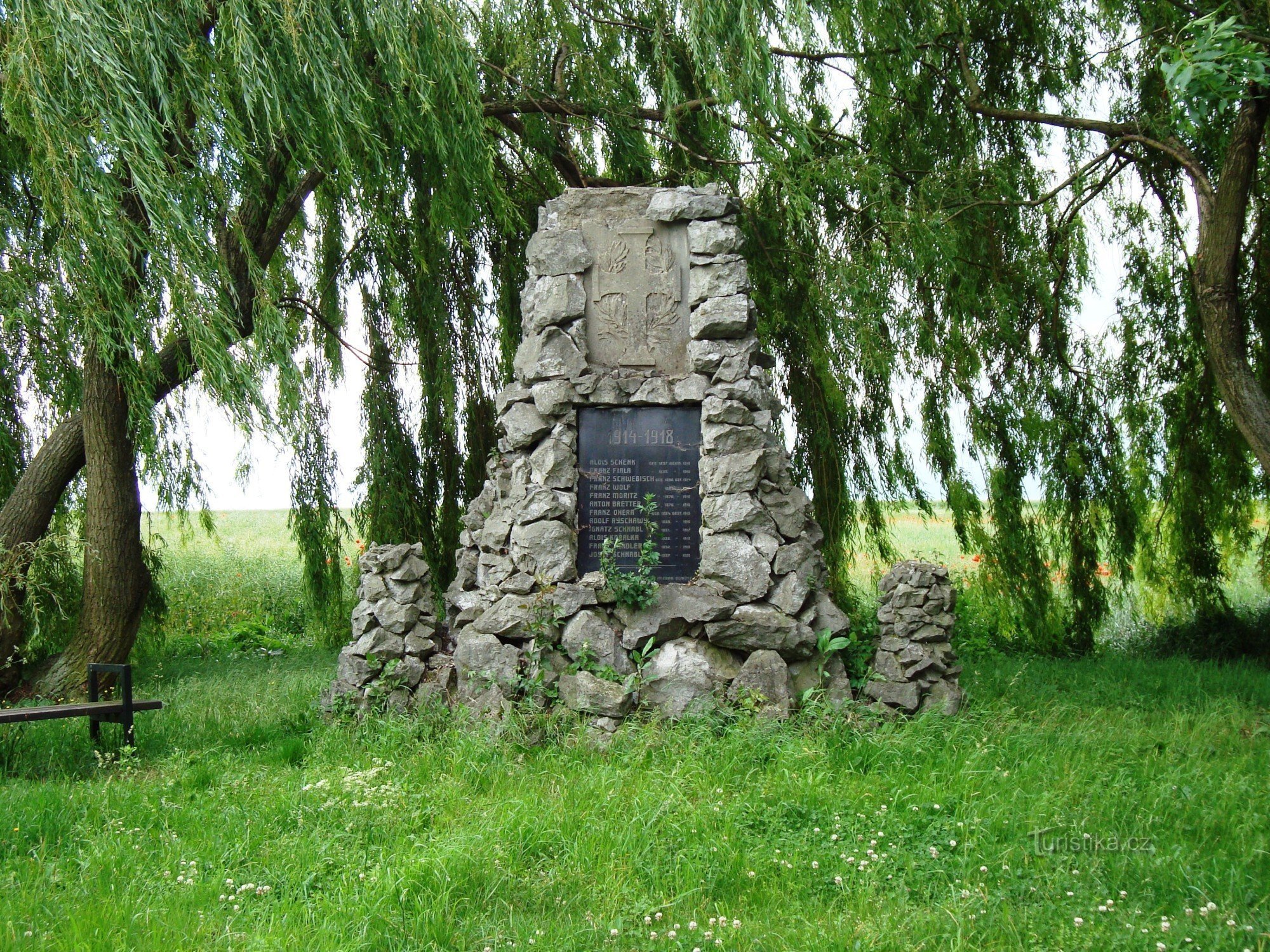 Parque Nedvězí al comienzo del pueblo con una cruz de reconciliación, una cruz de piedra de 1869 y un pom
