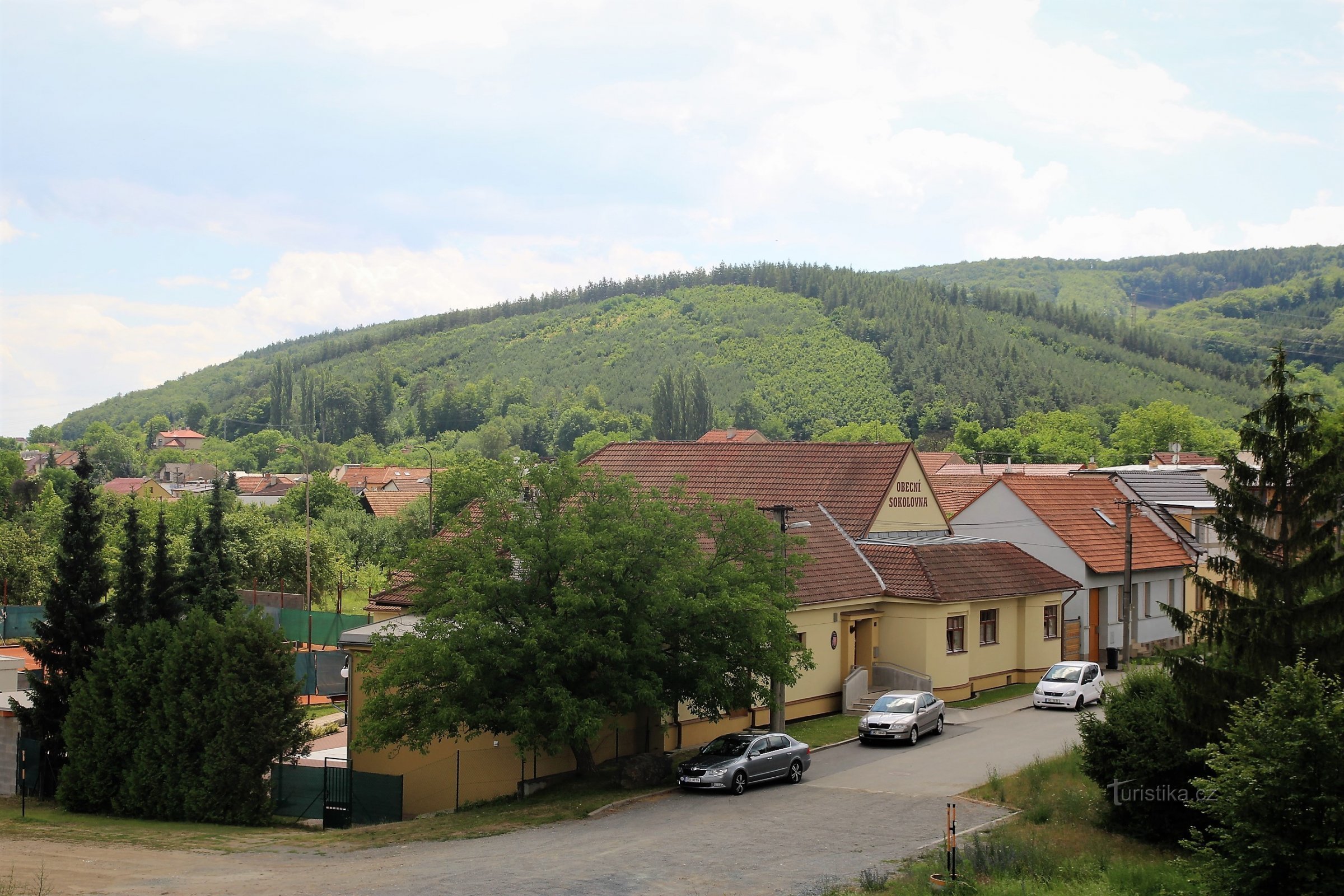Ostrá hora se zvedá přímo nad obcí Česká, za ní dominuje hlavní hřeben Baby