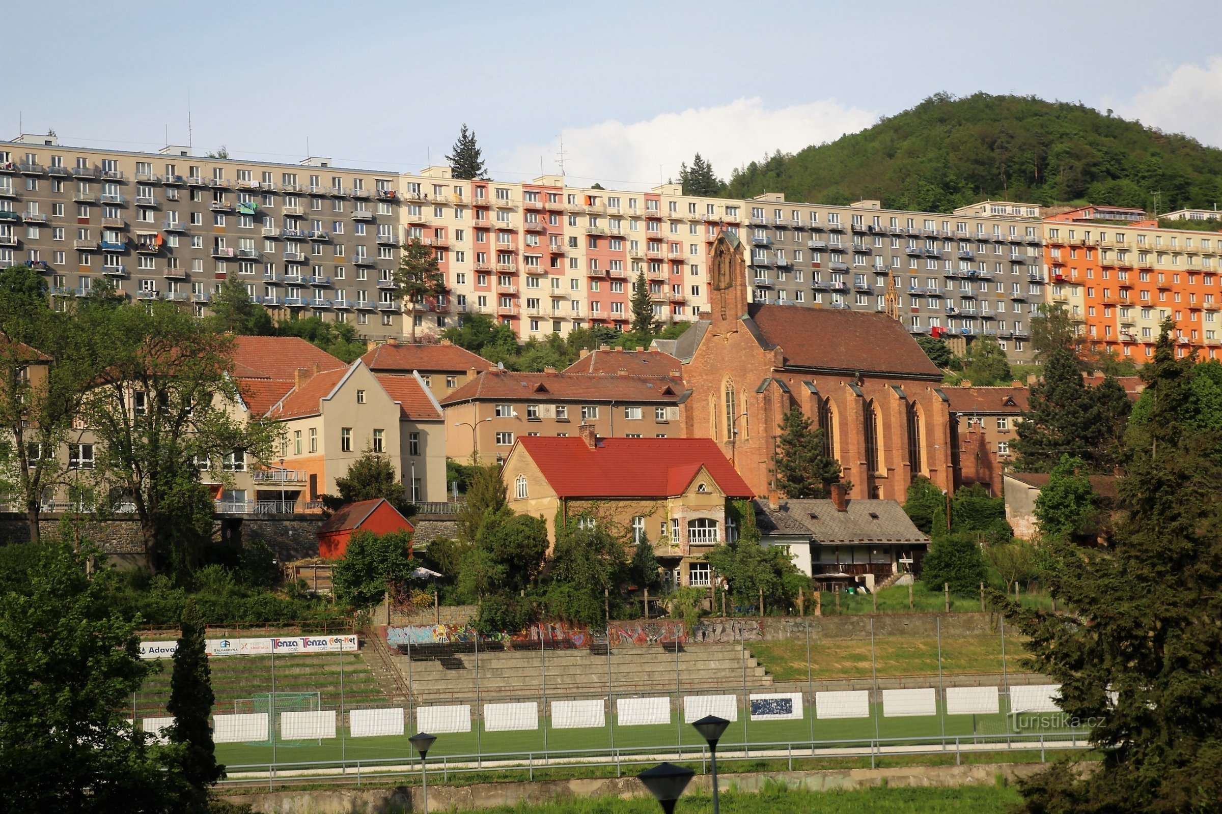 Панорама панельного дома Градчаны на улице Коменского, перед ним церковь св. Барбара