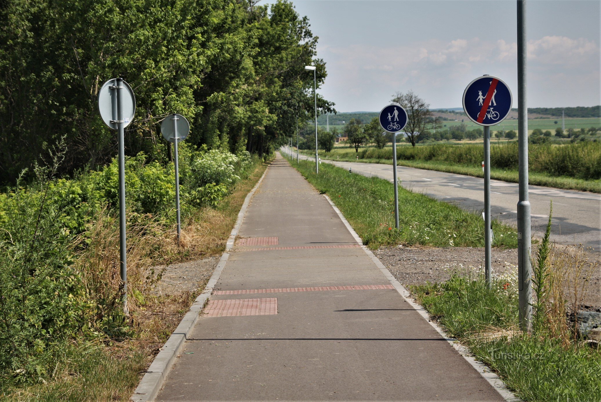 Een groen gemarkeerd toeristisch pad leidt langs het fietspad van het treinstation naar het dorp Zaječí