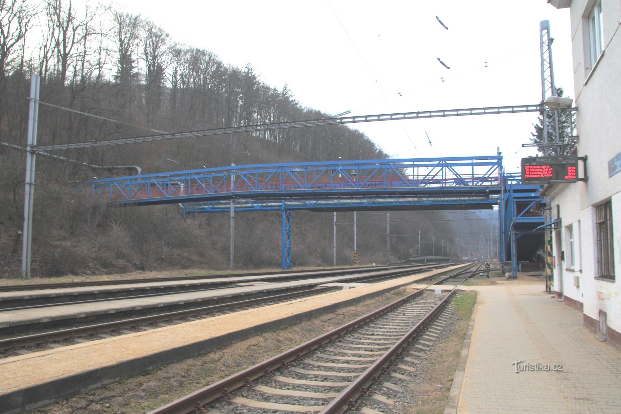 Άποψη της πεζογέφυρας από την αυλή του σιδηροδρόμου, πίσω από αυτήν η βιομηχανική γέφυρα από το λεβητοστάσιο Adastu