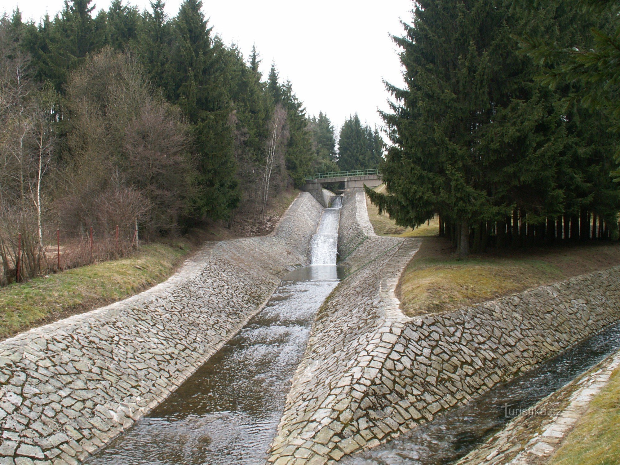 The stream from the Hrázka pond flows around the dam through an artificial channel