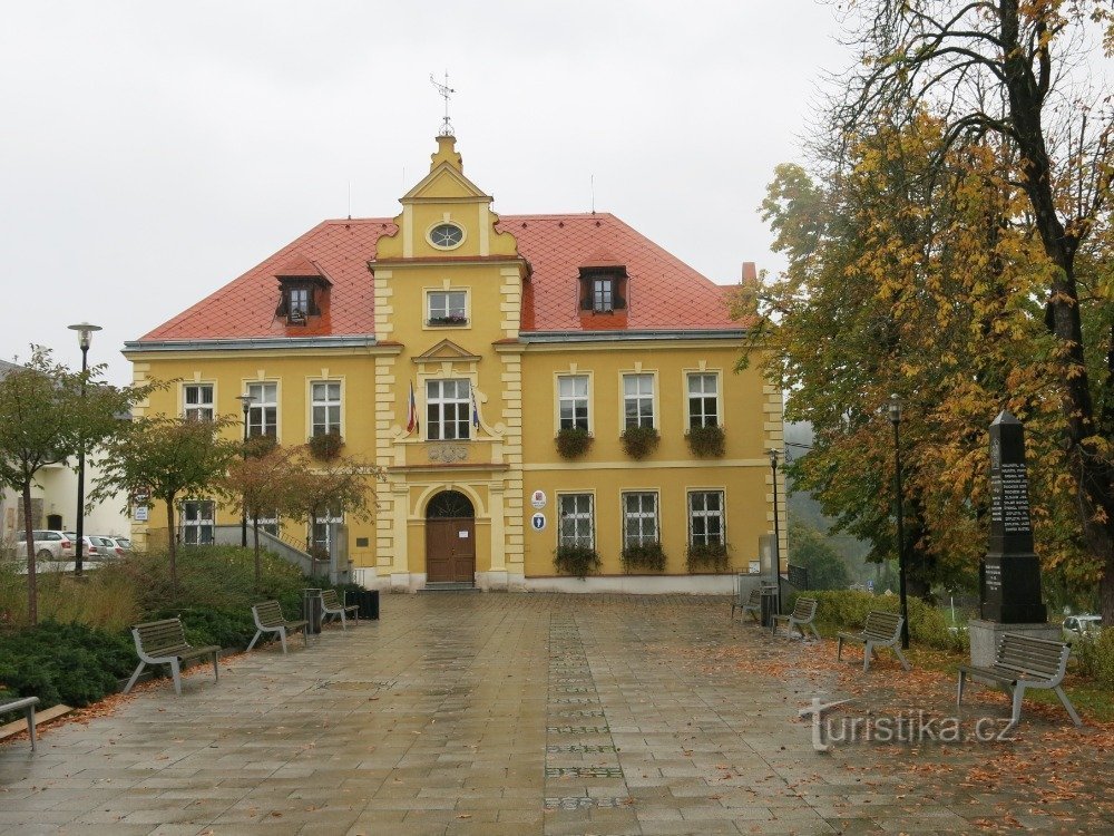 la fachada del edificio de la oficina municipal, a la derecha el monumento a las víctimas de la guerra