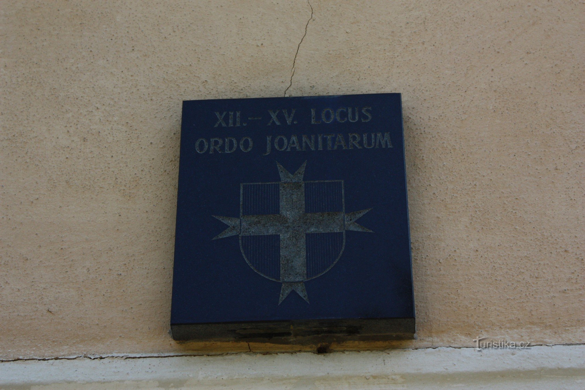 Zakonny herb joannitów nad wejściem do kościoła w Orlovicach