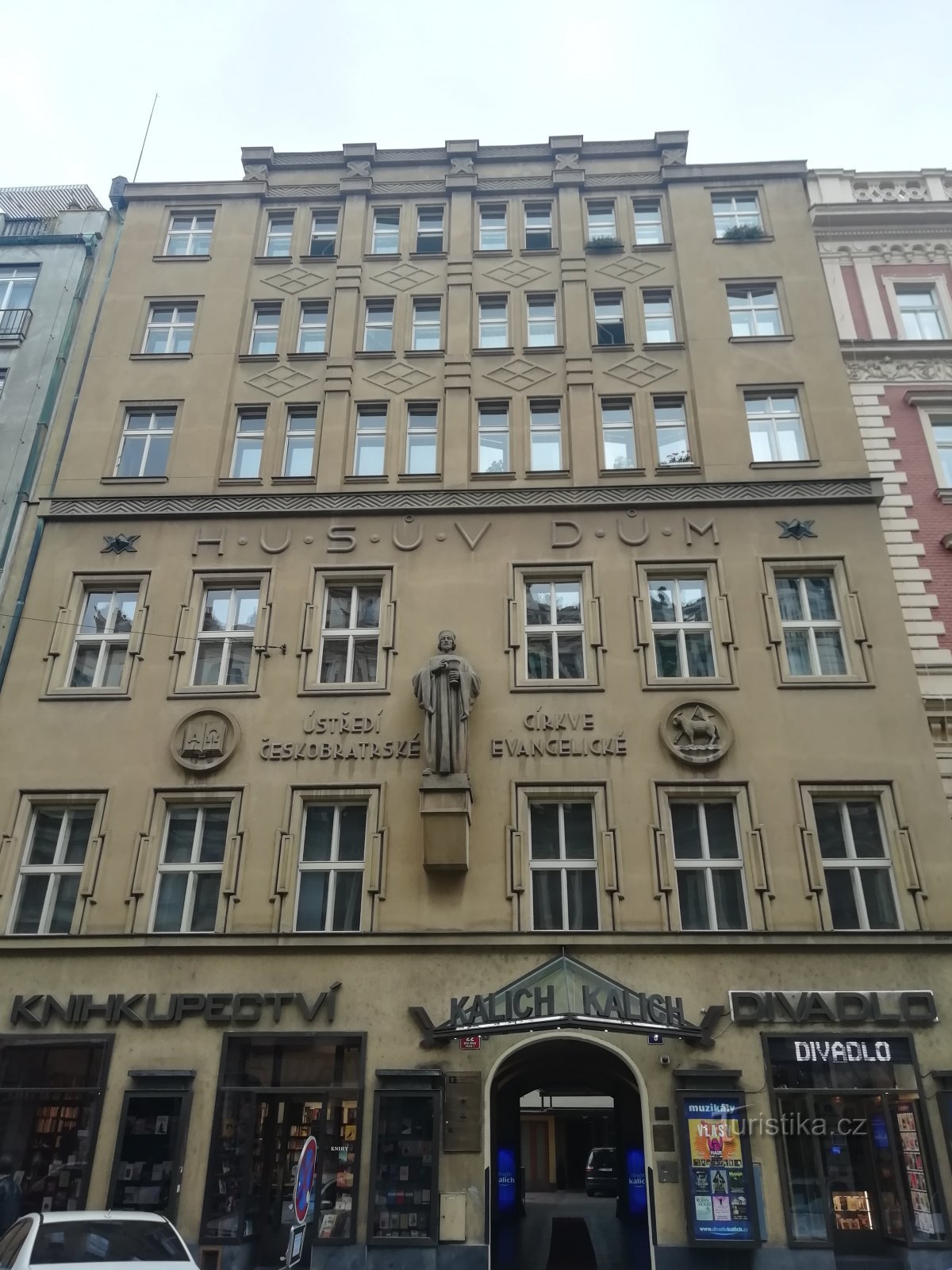 une corniche au-dessus de l'inscription Husův Dům sépare les étages nouvellement ajoutés de ceux d'origine