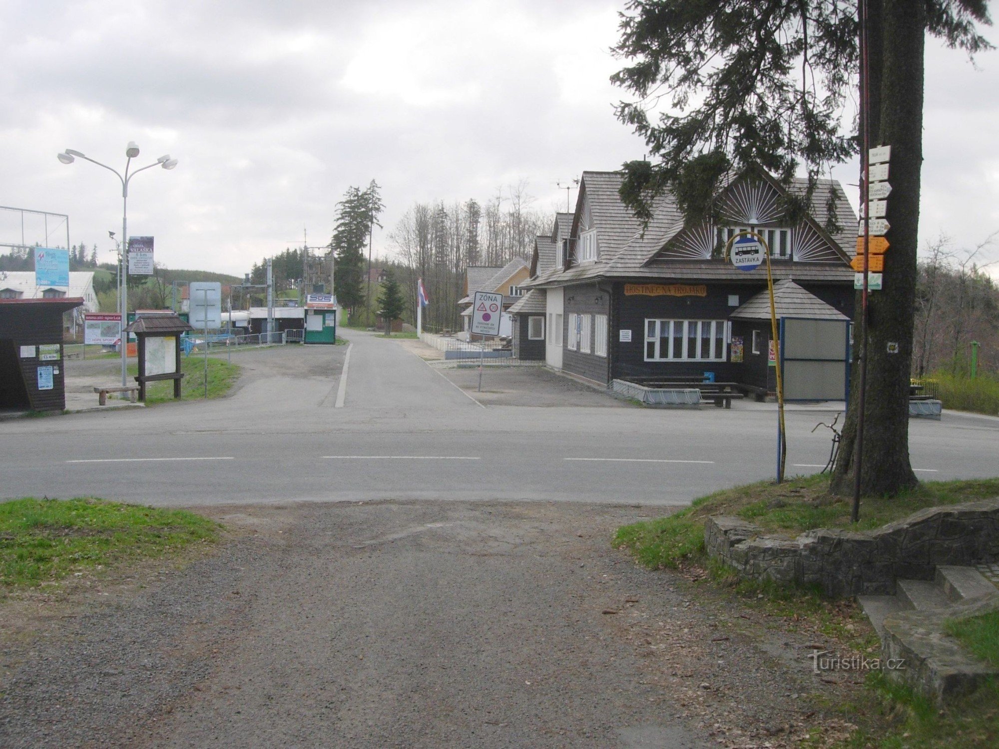 Een driewegkruising met een herberg, een bushalte, een skigebied en een wegwijzer