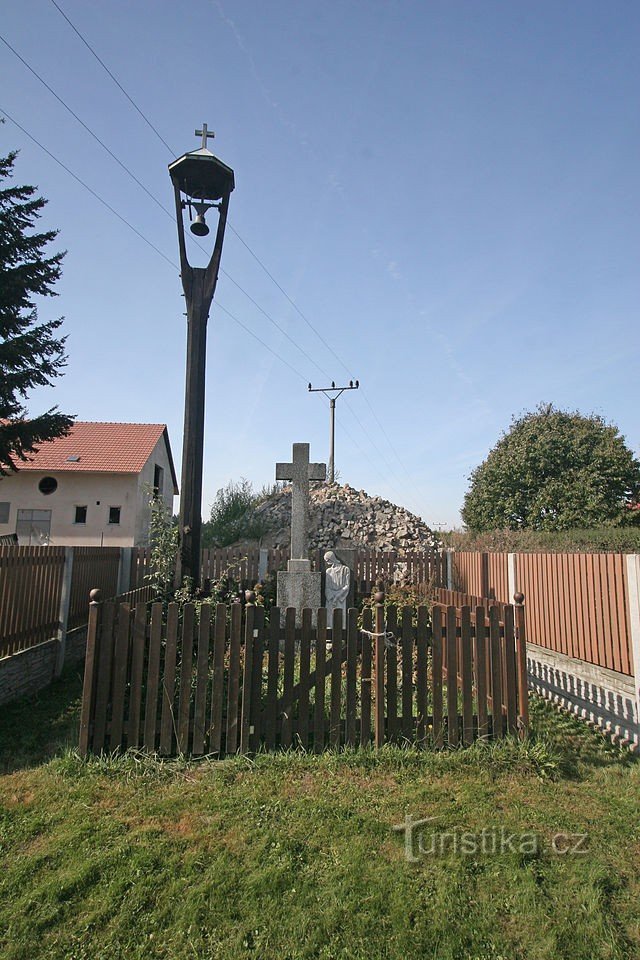 a modest cross with a bell is located right next to the road