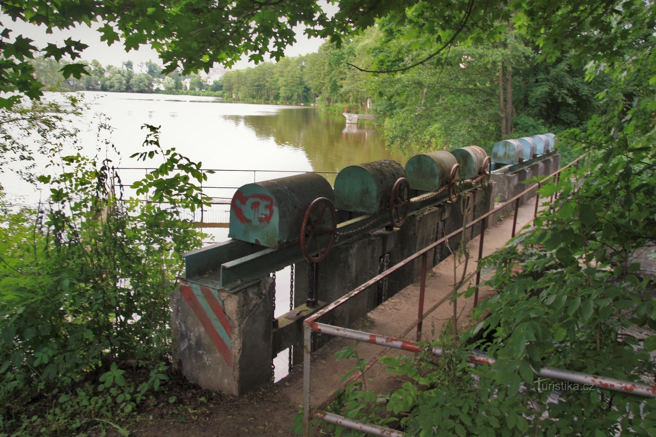 The sluice gate at the outlet of the pond, a red sign leads along the footbridge