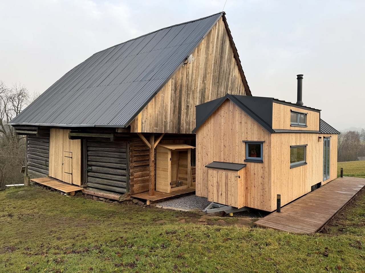 Stodola, která domeček odděluje od zbytku vesnice. Pod ní je možno zaparkovat.