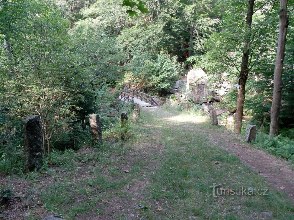 Štolpišská silnice u dřevěné lávky přes potok Černý Štolpich, pomníček je na str