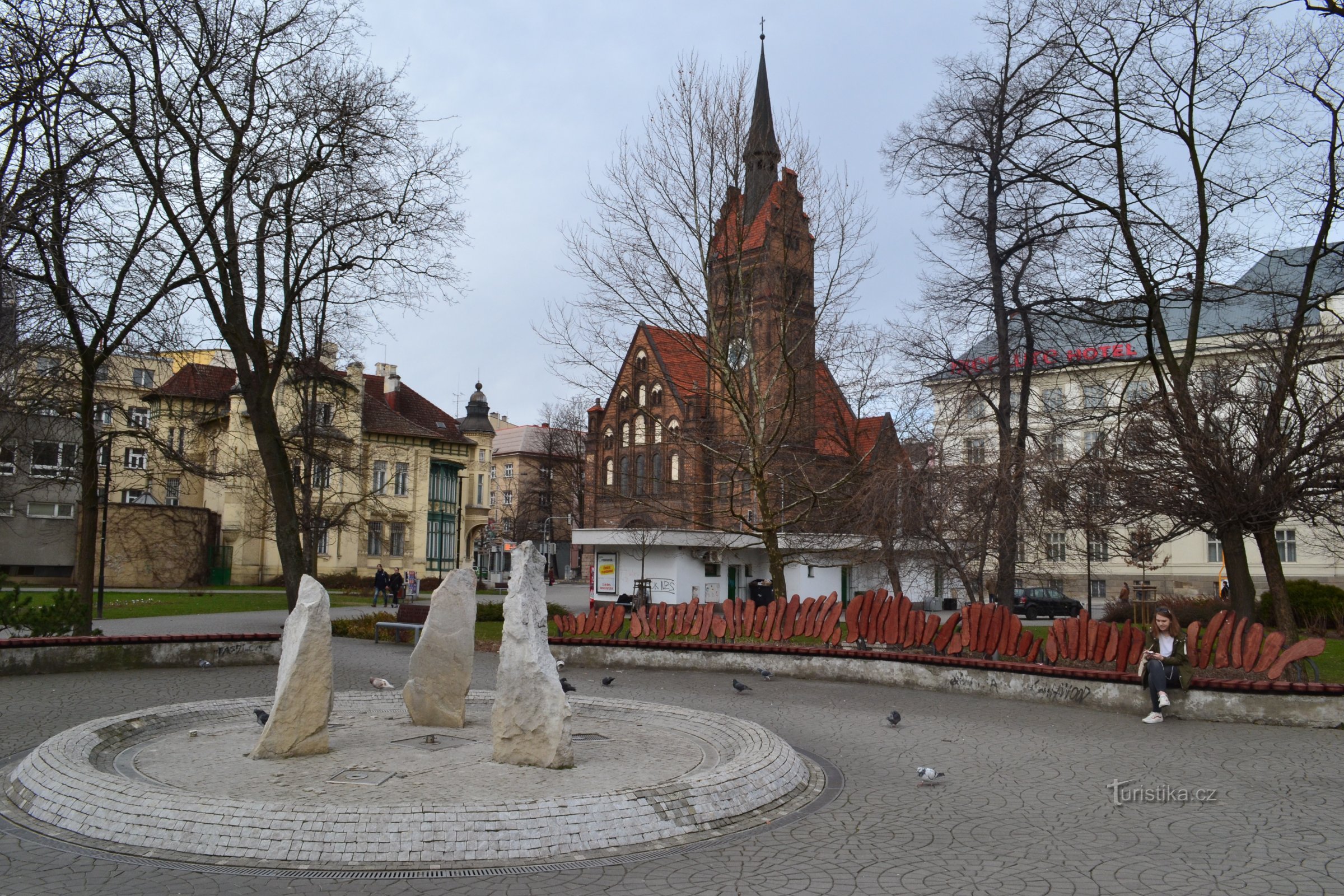 a fountain with three stones and an interesting maxi bench