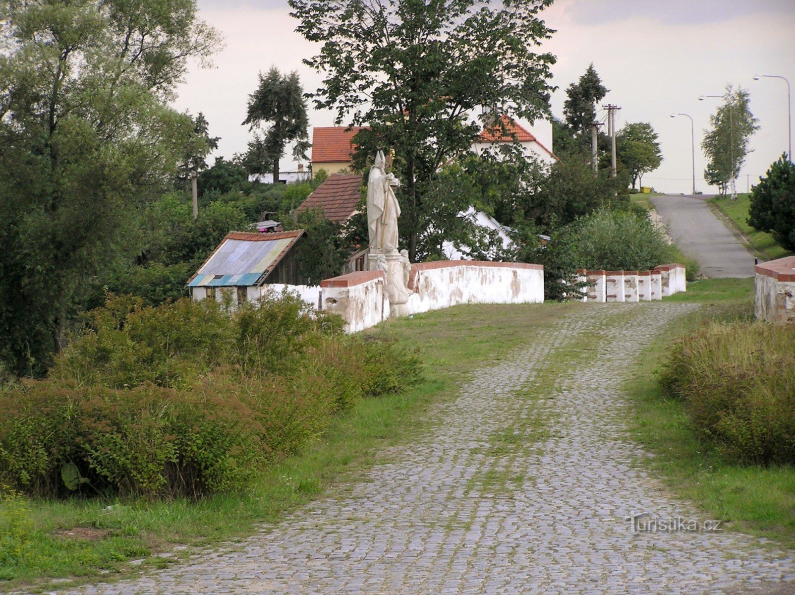 a régi császári aszfaltozott út jó állapotú szakasza híddal (rajta Szent Miklós szobor)